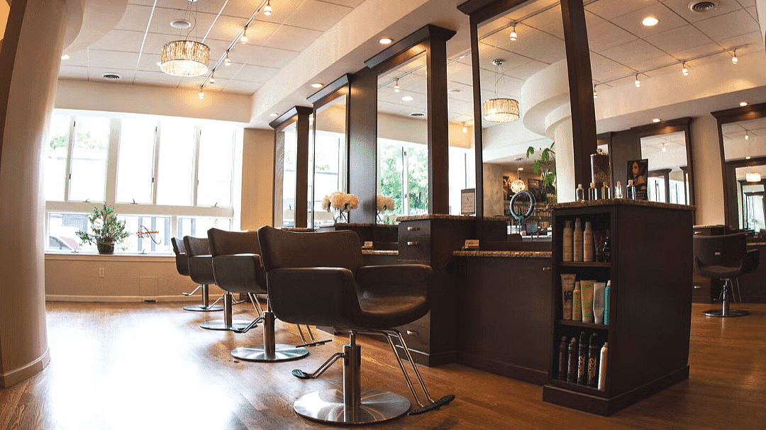 Modern hair salon with stylish chairs, large mirrors, and elegant lighting.